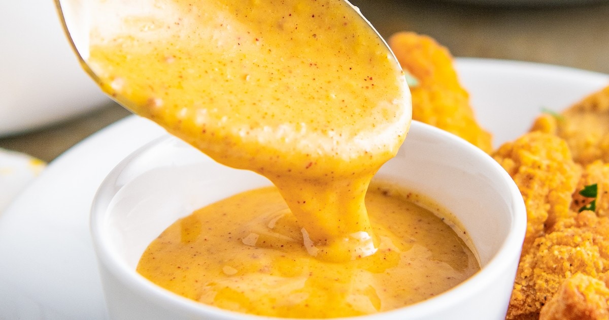 Close up of a spoon lifting out of a bowl of honey mustard dip