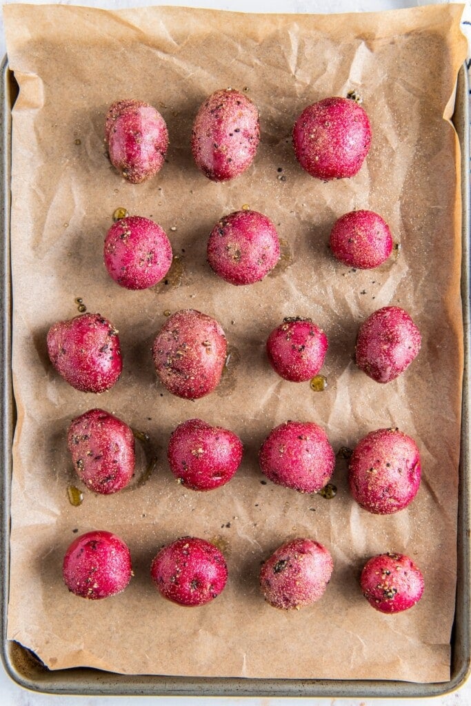 Baby potatoes on a sheet lined with parchment paper.