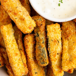 Overhead close-up view of zucchini fries on a plate with a bowl of ranch