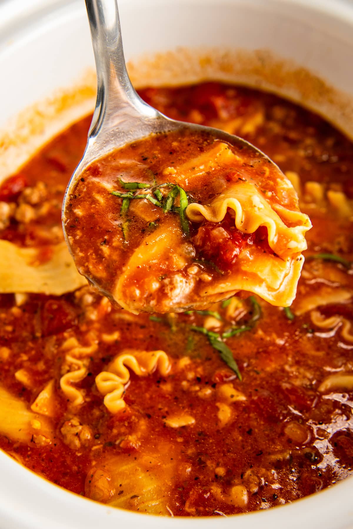 Close up of a spoonful of lasagna soup over a bowl of lasagna soup