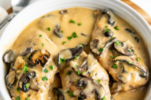 Chicken breasts in a serving dish with gravy, mushrooms, and parsley