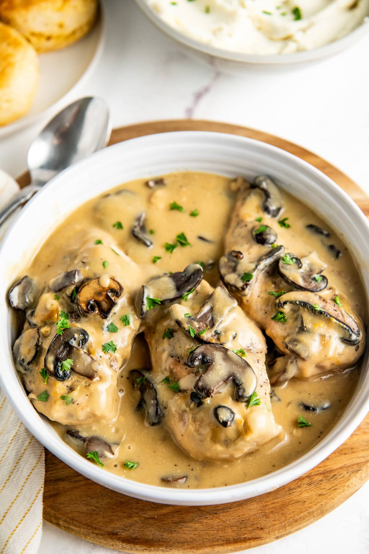 Chicken breasts in a serving dish with gravy, mushrooms, and parsley
