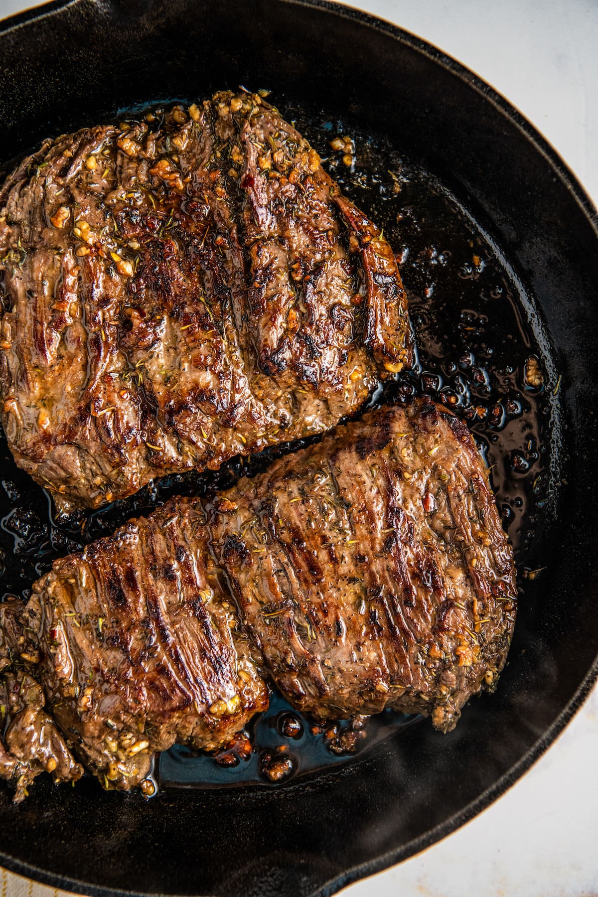 Overhead view of two skirt steaks in a cast iron skillet