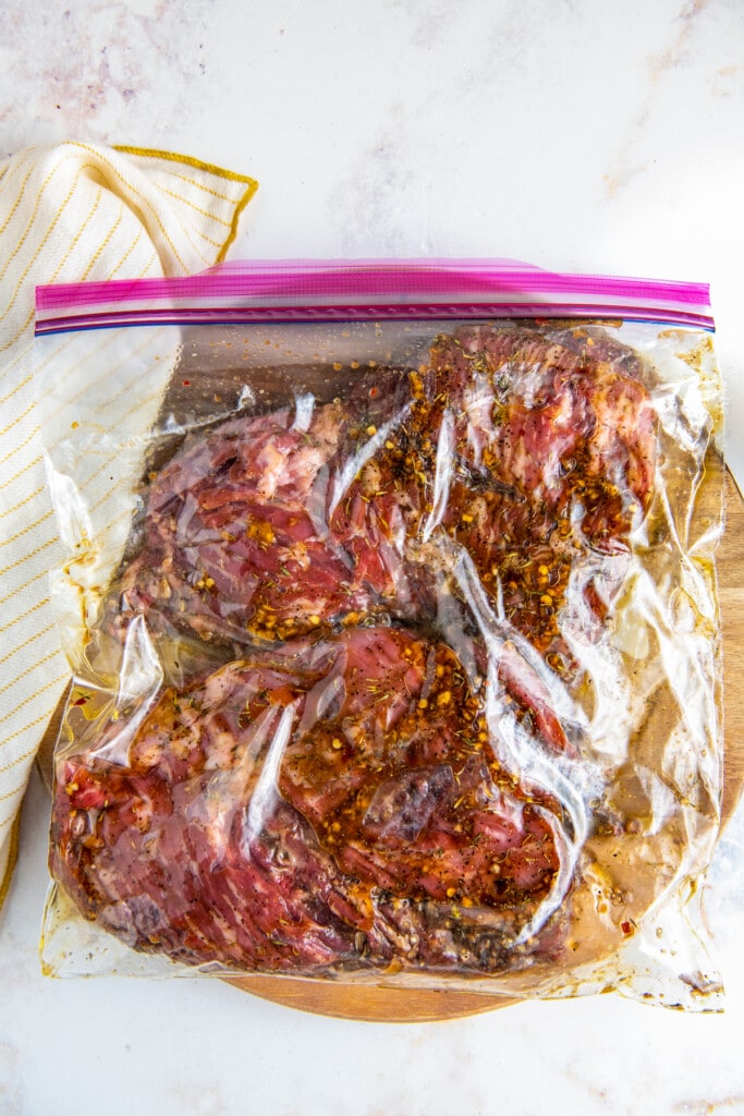 Two skirt steaks in a sealed ziplock bag with marinade