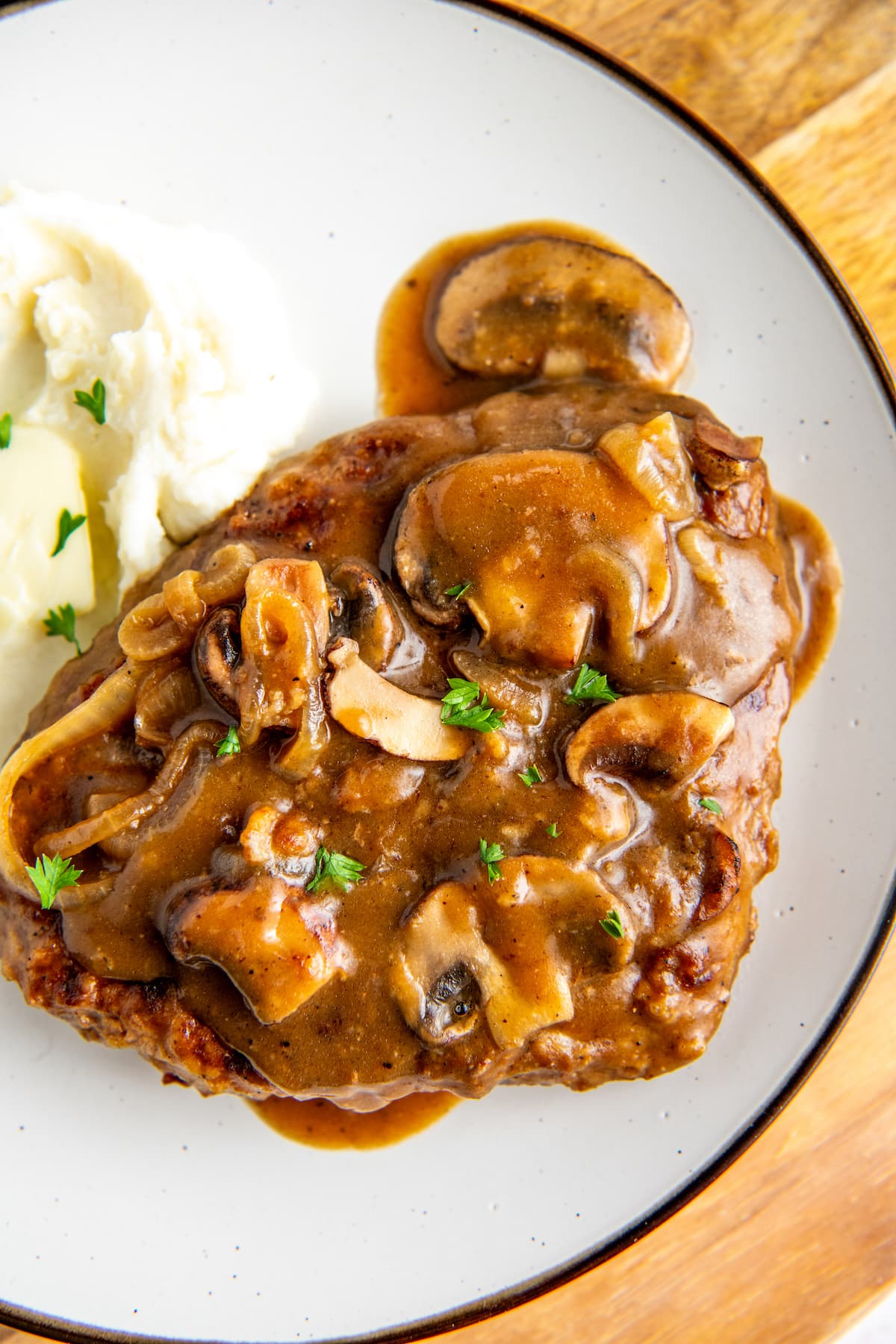 Overhead view of a steak covered in gravy and mushrooms