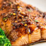 Close up of a piece of salmon on a plate covered in a chili sauce