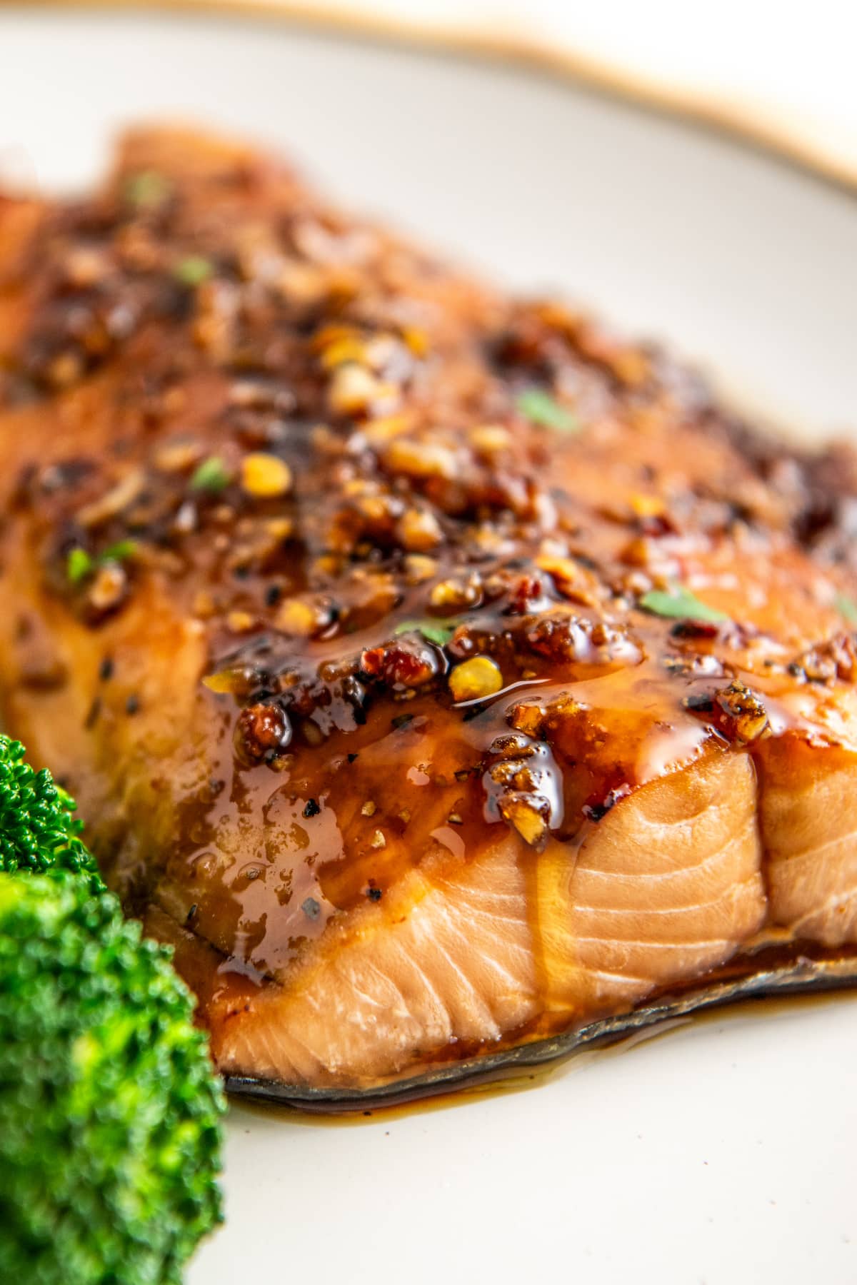 Close up of a piece of salmon on a plate covered in a chili sauce.