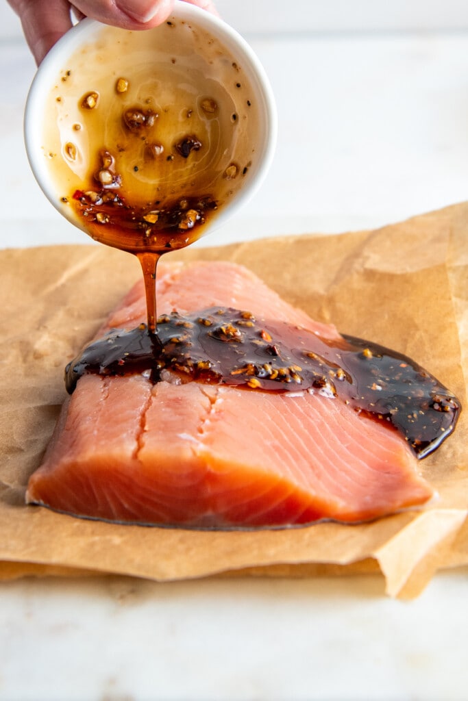 Soy, honey, and garlic sauce being poured over a piece of salmon