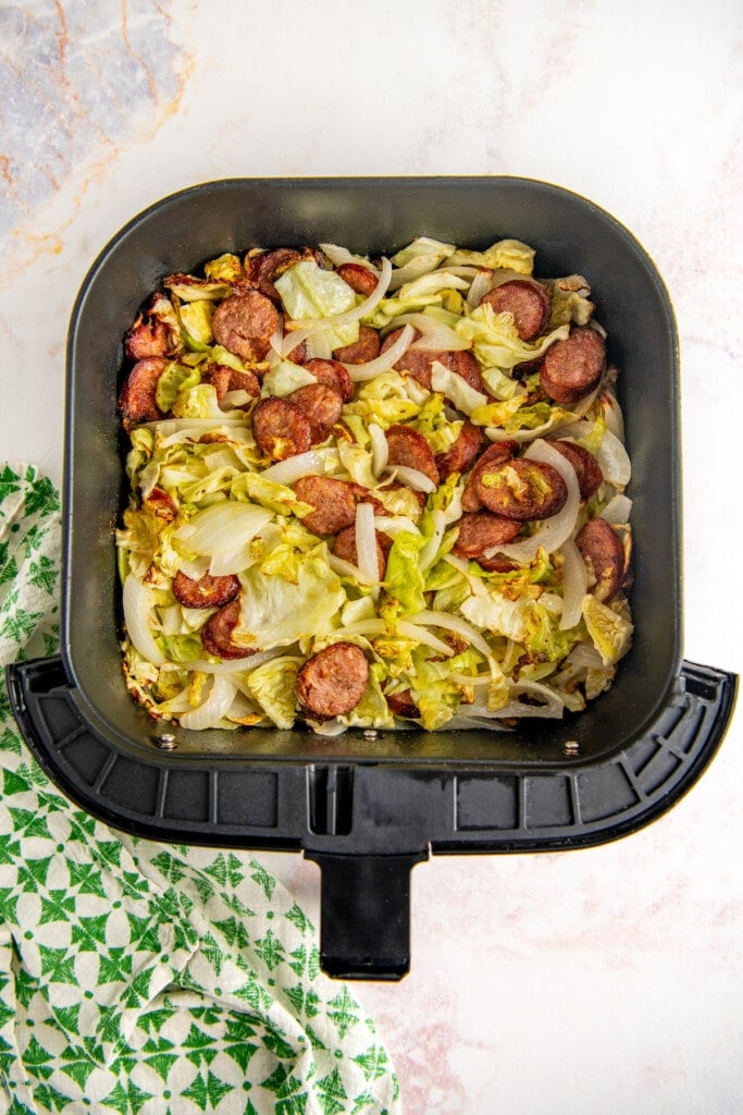 Cooked smoked sausage, cabbage, and onions in an air fryer basket