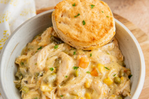 A bowl of chicken pot pie filling with a biscuit on top