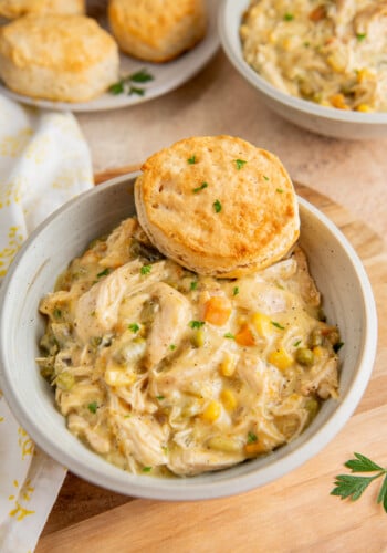A bowl of chicken pot pie filling with a biscuit on top