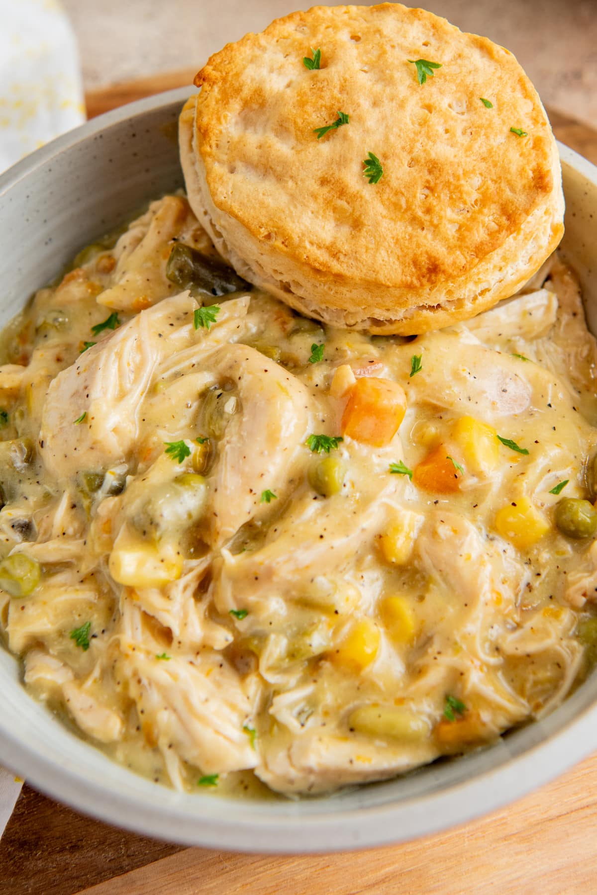 Close up of a bowl of chicken pot pie filling with a biscuit.