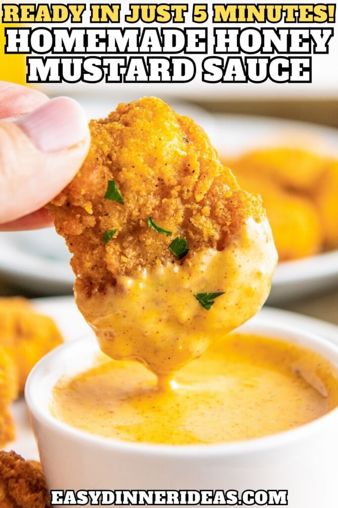 A bowl of honey mustard sauce with a piece of chicken being dunked into it.