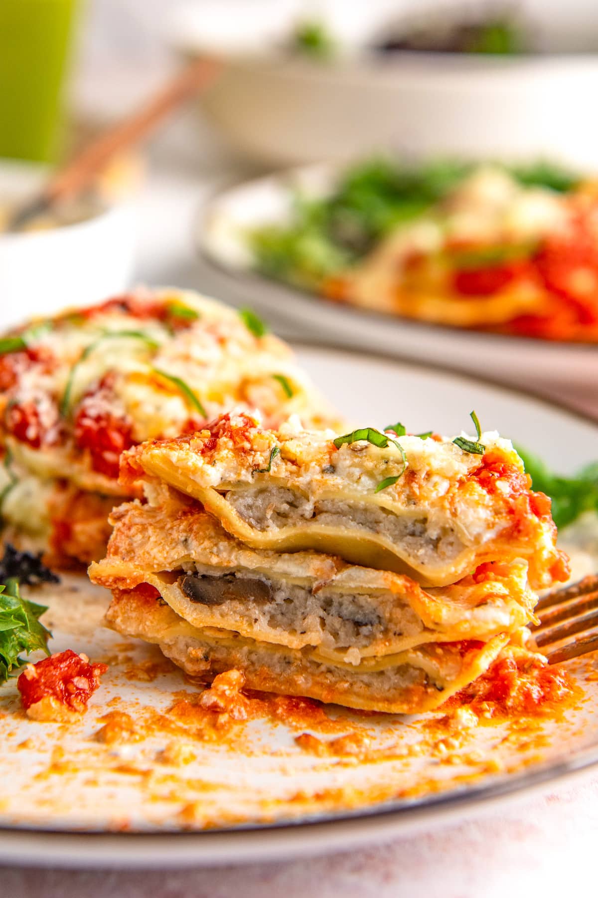 A stack of ravioli on a plate, cut in half with a fork on the side