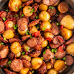 Overhead view of a skillet of sausage and potatoes with onions and peppers