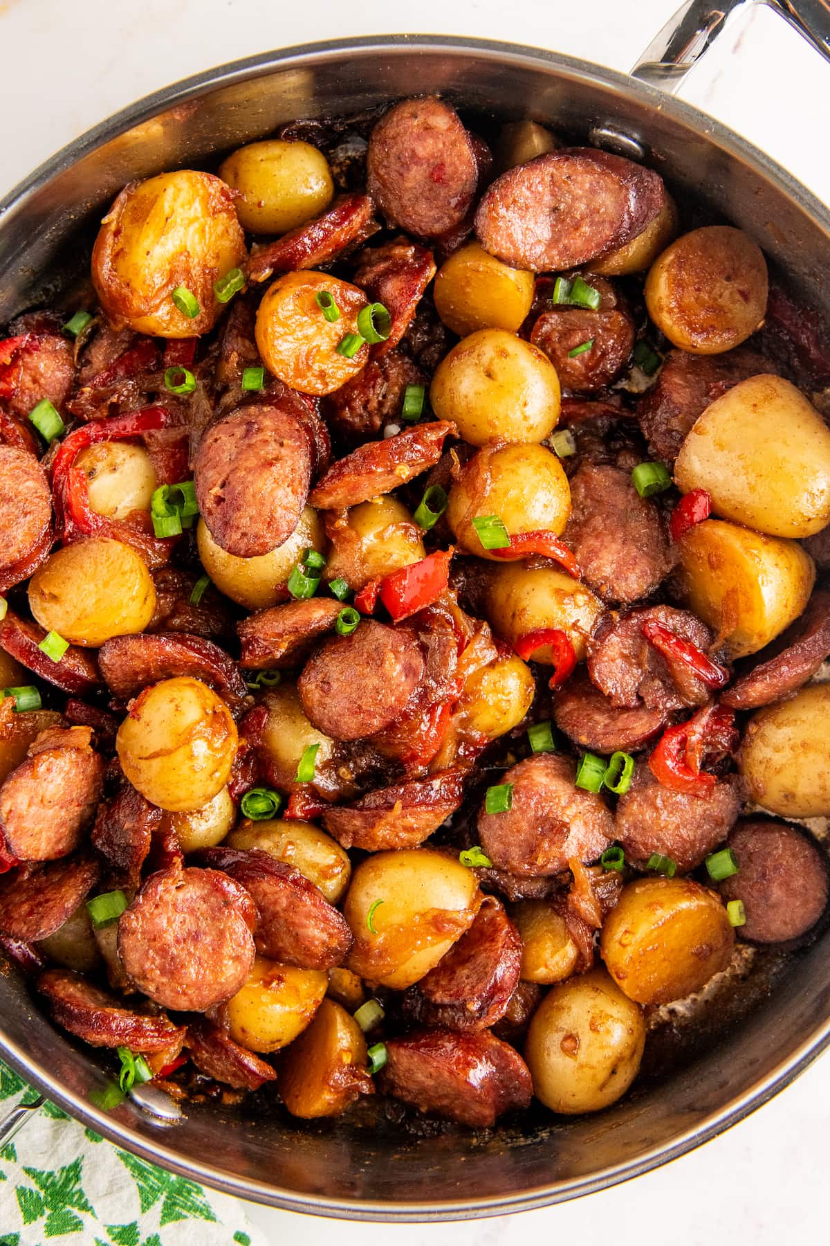 Overhead view of a skillet of sausage and potatoes with onions and peppers