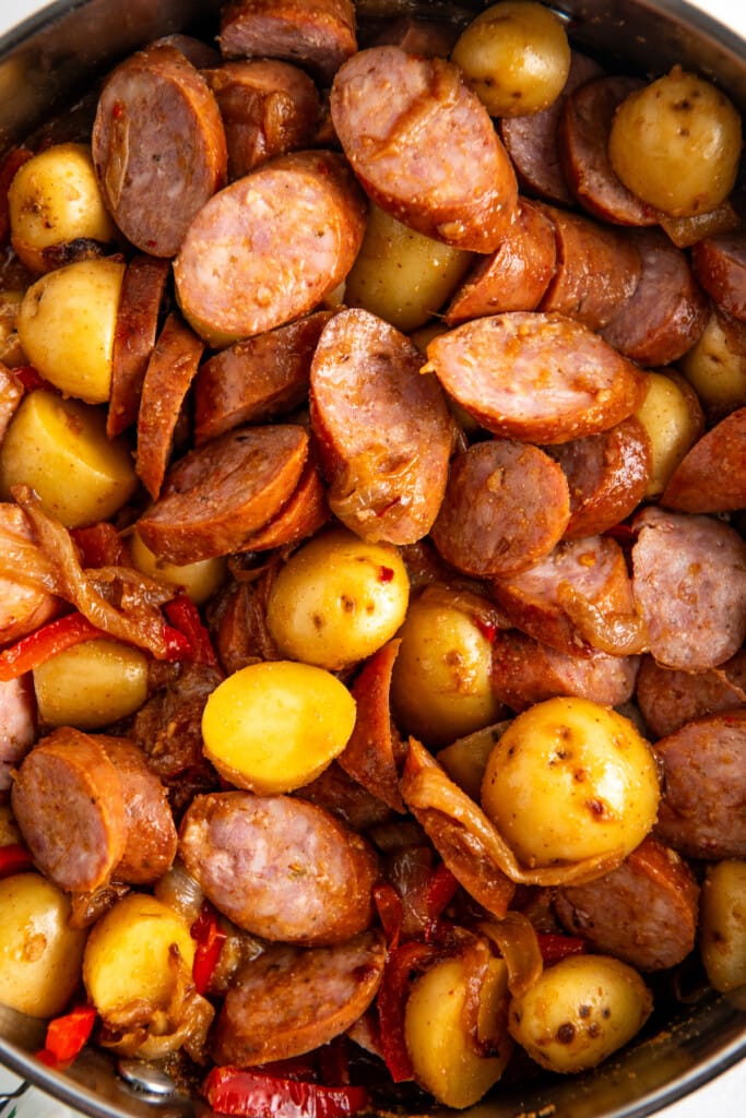 A skillet filled with uncooked sausage and potatoes