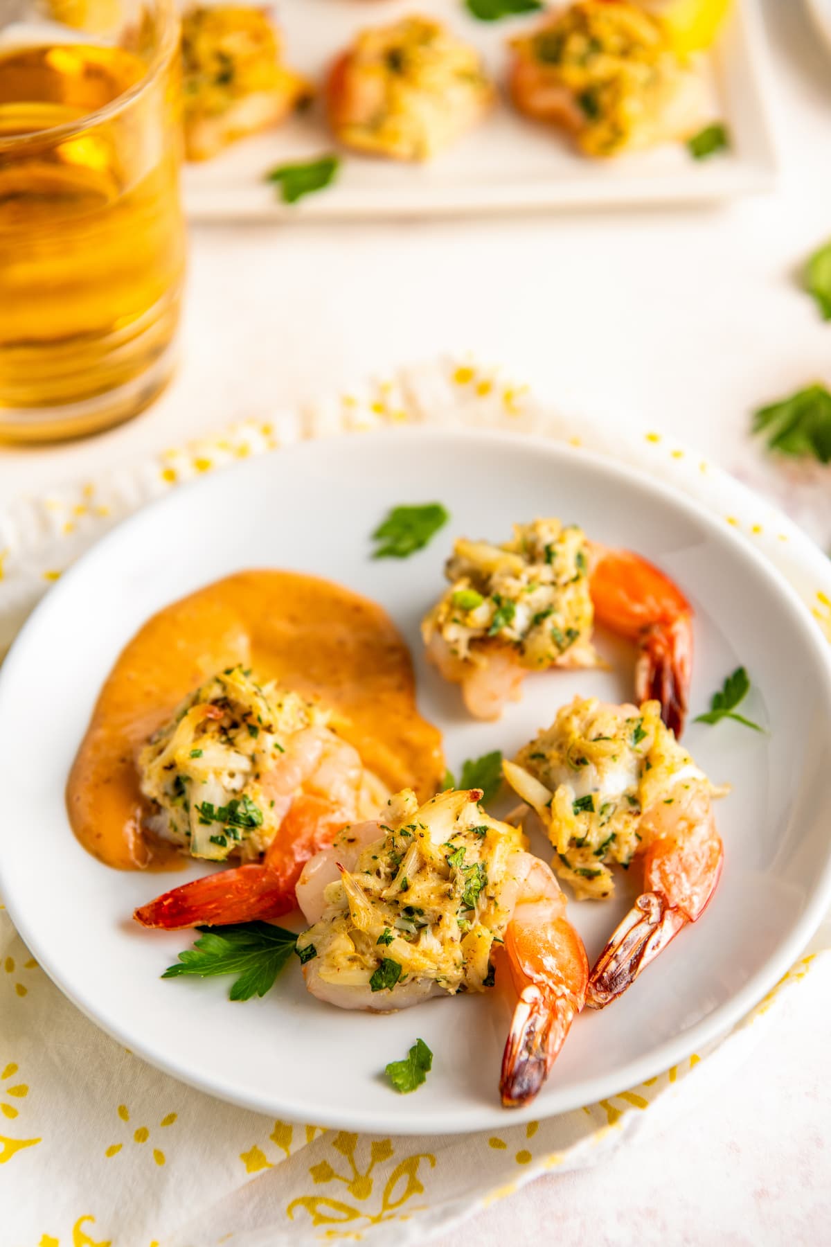 Baked stuffed shrimp on a small plate with sauce.