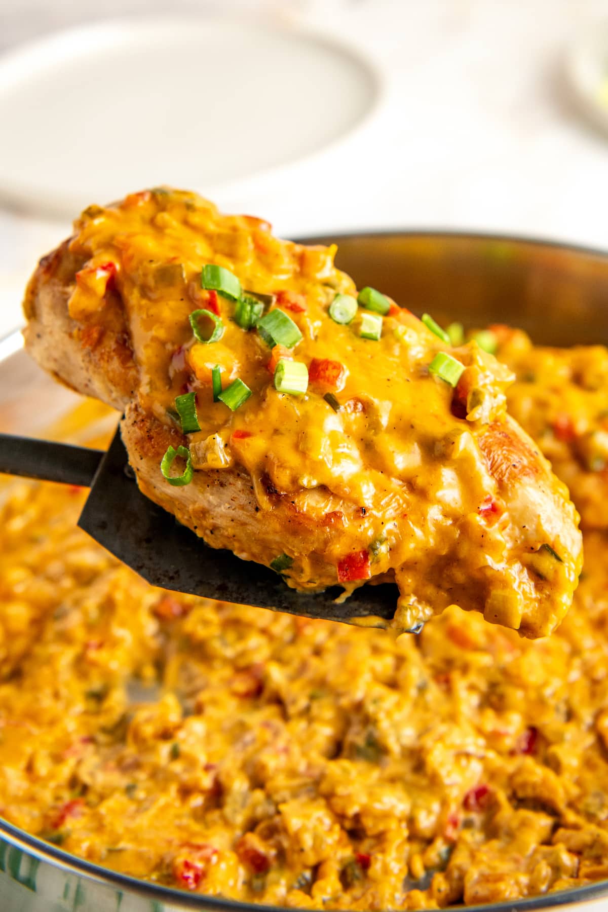 Lifting a chicken breast in a Cajun cream sauce out of a skillet.