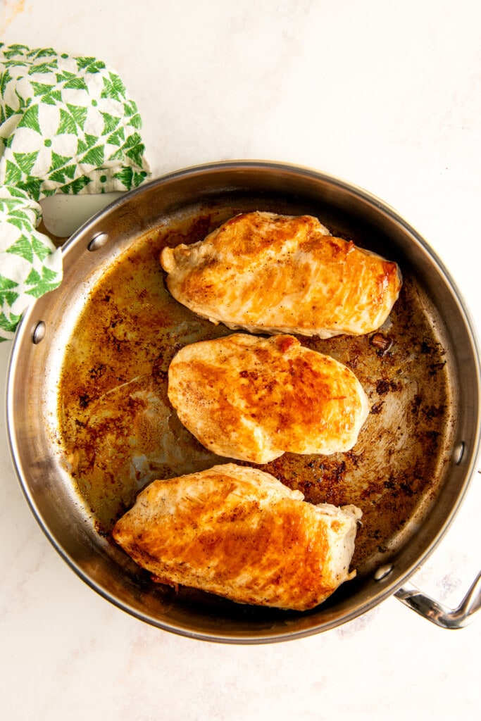 Seasoned chicken cooking in a skillet.