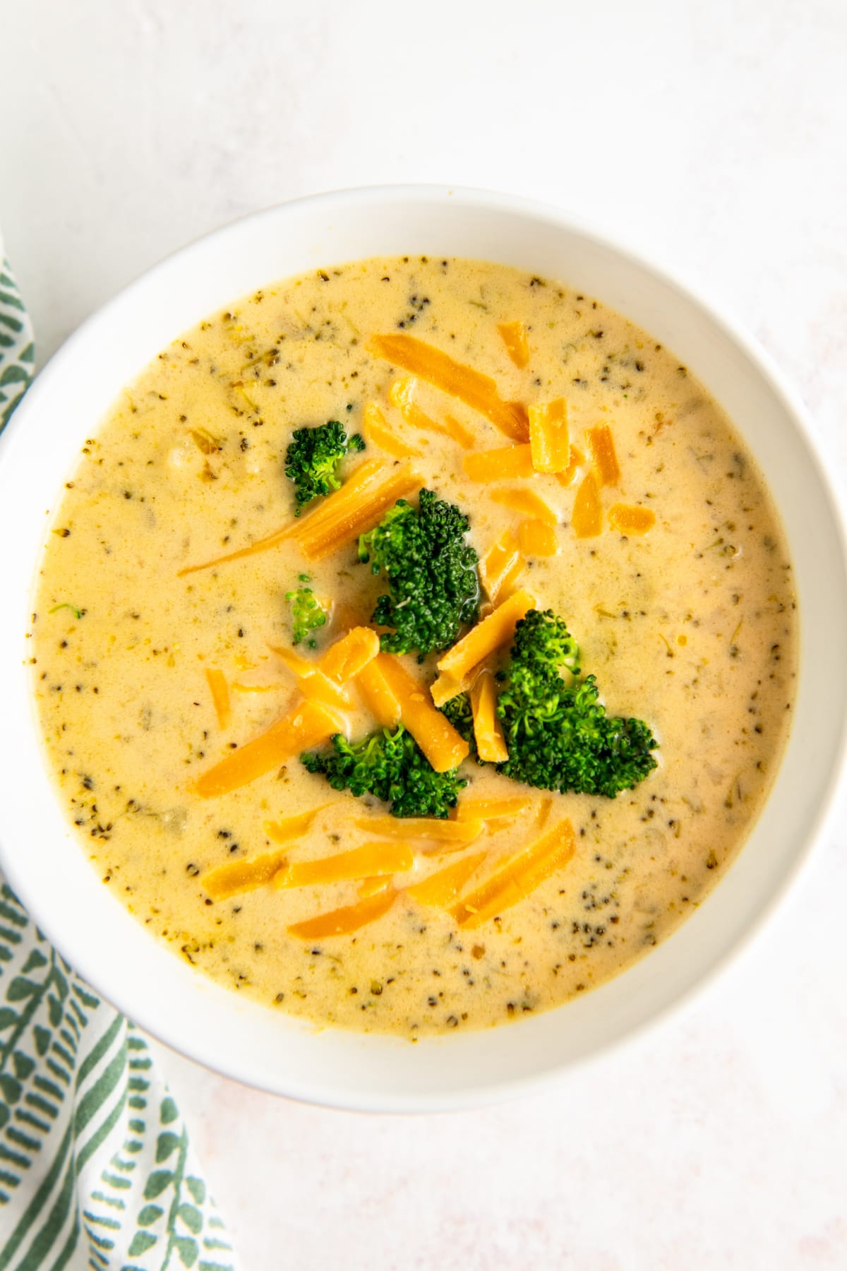 Overhead shot of crockpot broccoli cheese soup served in a white bowl.