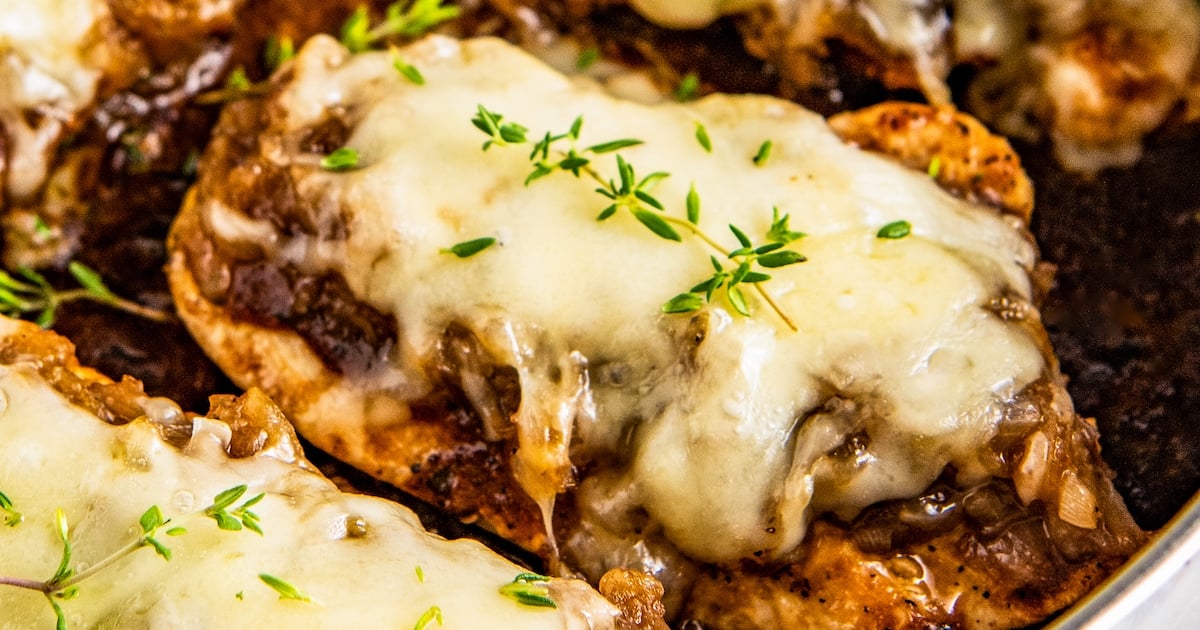 French onion chicken with melted gruyere cheese on top in a skillet.