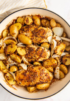 Overhead shot of honey mustard chicken with potatoes and onions in a baking dish.