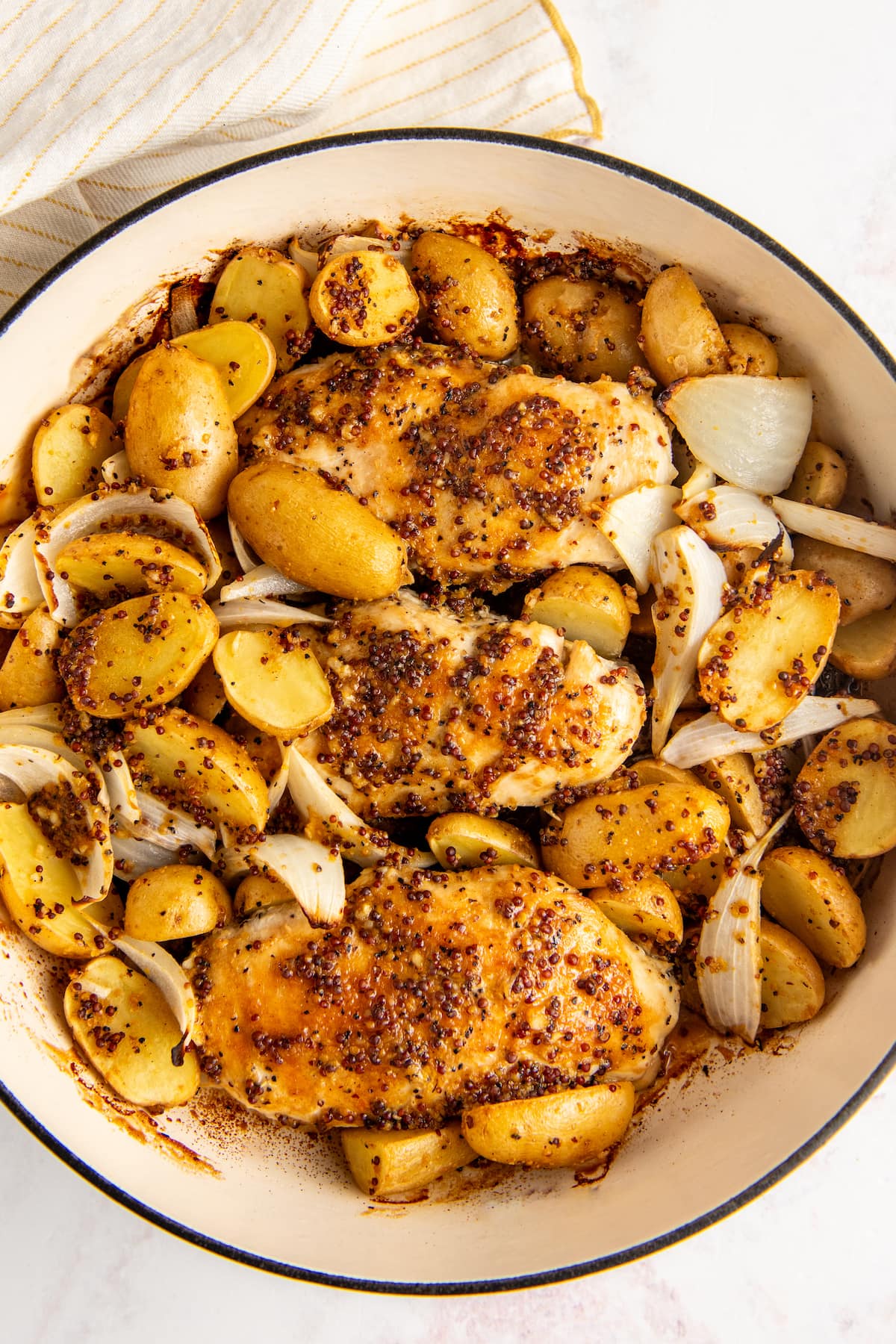 Overhead shot of honey mustard chicken with potatoes and onions in a baking dish.