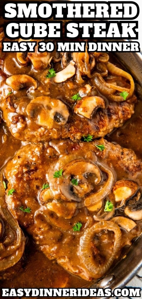 Smothered cube steak in a brown gravy in a skillet.