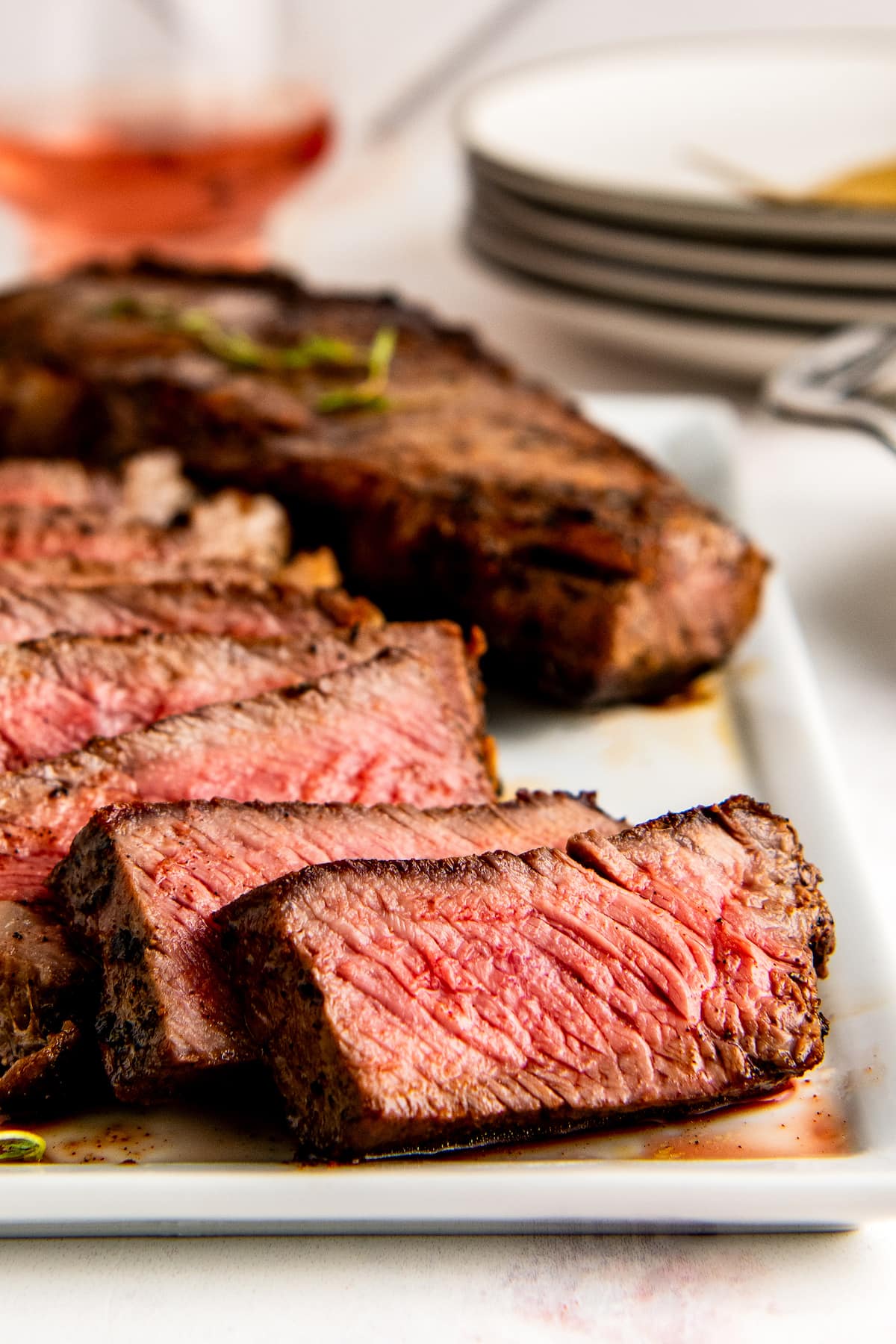 Slices of steak on a white serving platter.