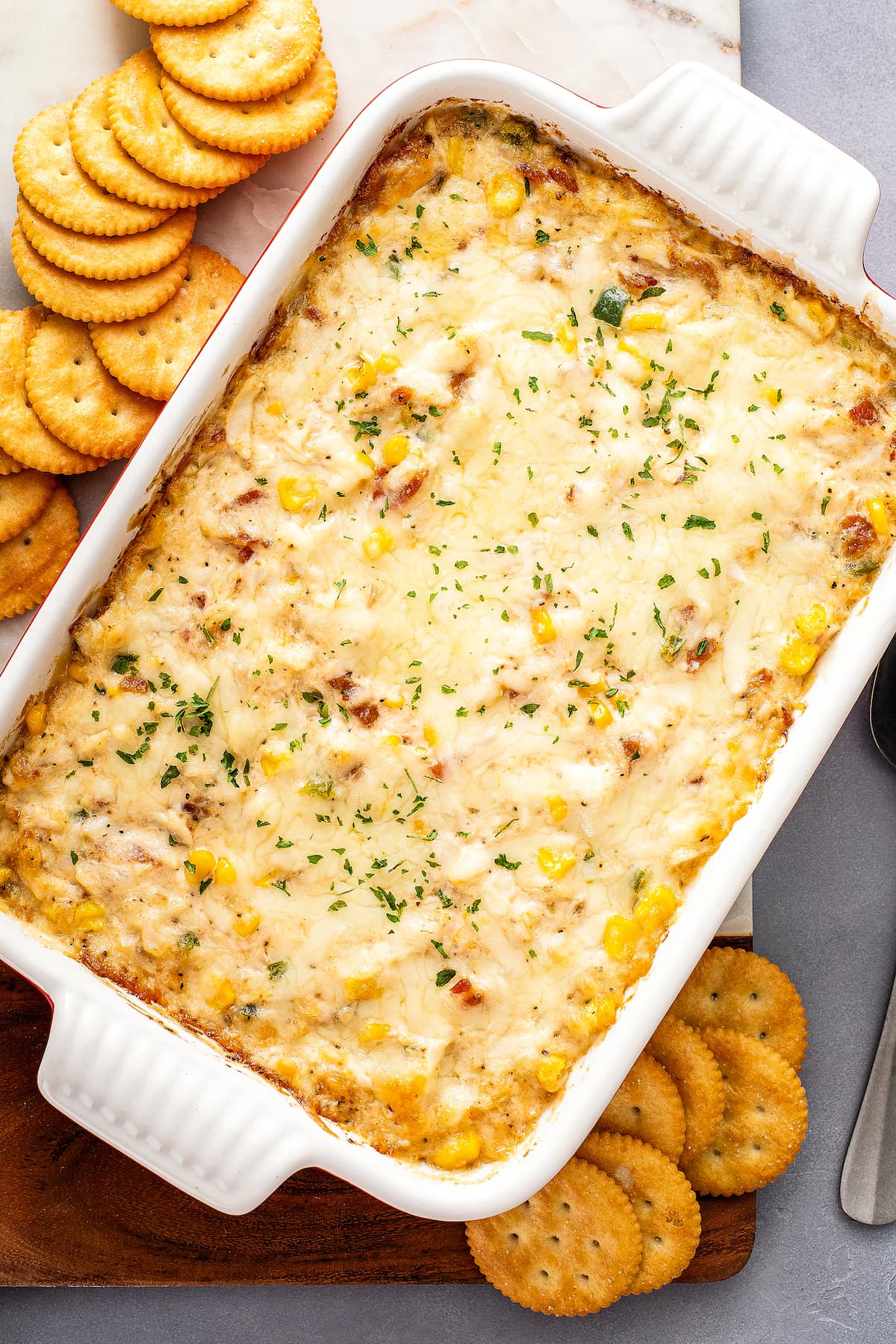 Overhead view of a casserole dish full of hot crab dip, surrounded by Ritz crackers.