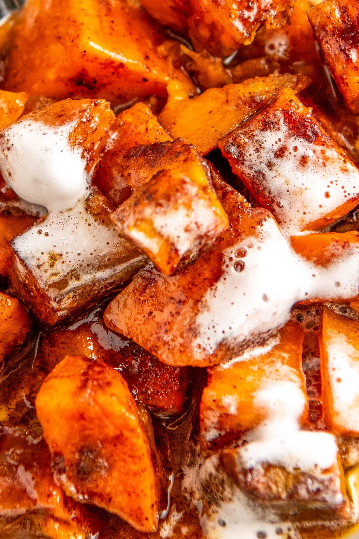 Close up of seasoned sweet potato cubes covered in melted marshmallows.