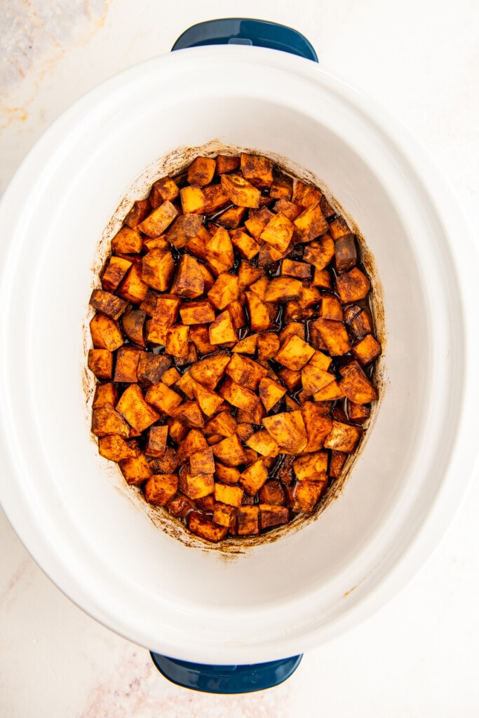 Overhead view of cooked and season sweet potato cubes in a crockpot.