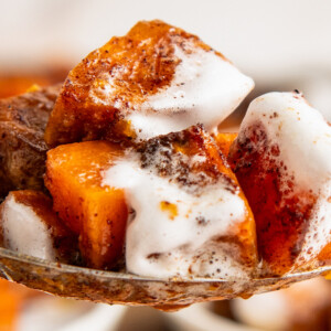 Close up of a spoon of sweet potato casserole covered in melted marshmallows.