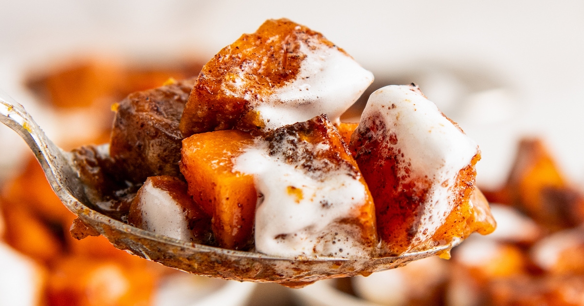 Close up of a spoon of sweet potato casserole covered in melted marshmallows.