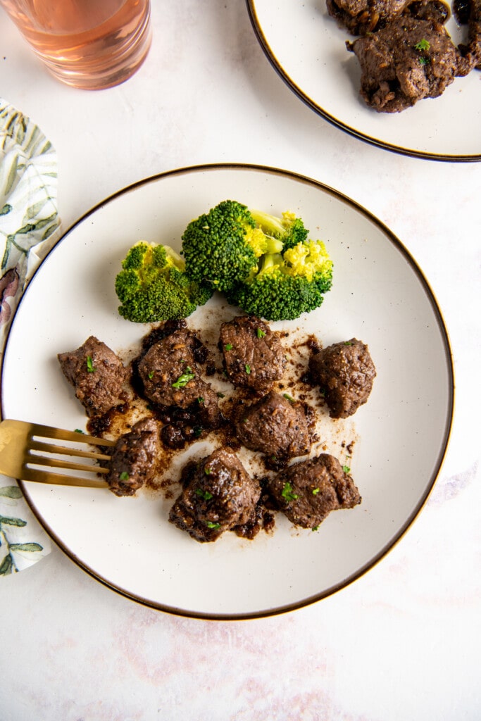 Overhead view of a plate filled with broccoli and steak bites, with a fork.