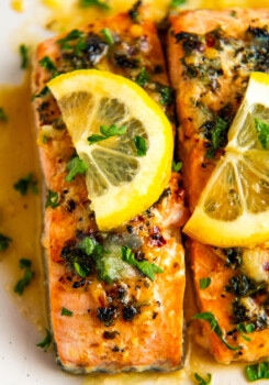 Close up overhead view of salmon fillets topped with lemon and parsley.