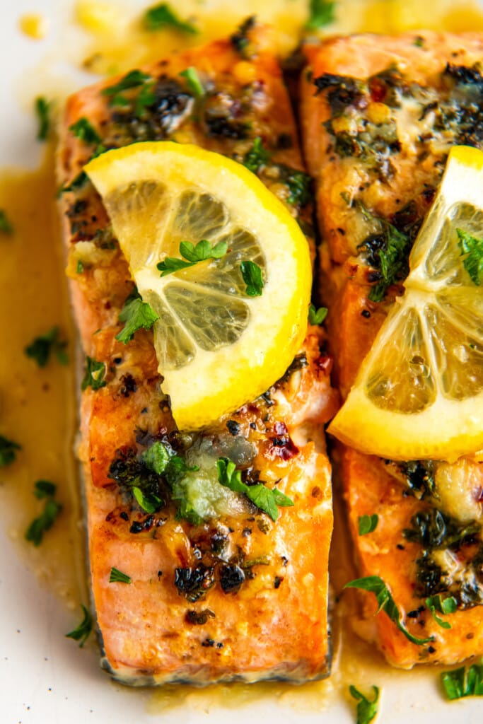 Close up overhead view of salmon fillets topped with lemon and parsley.