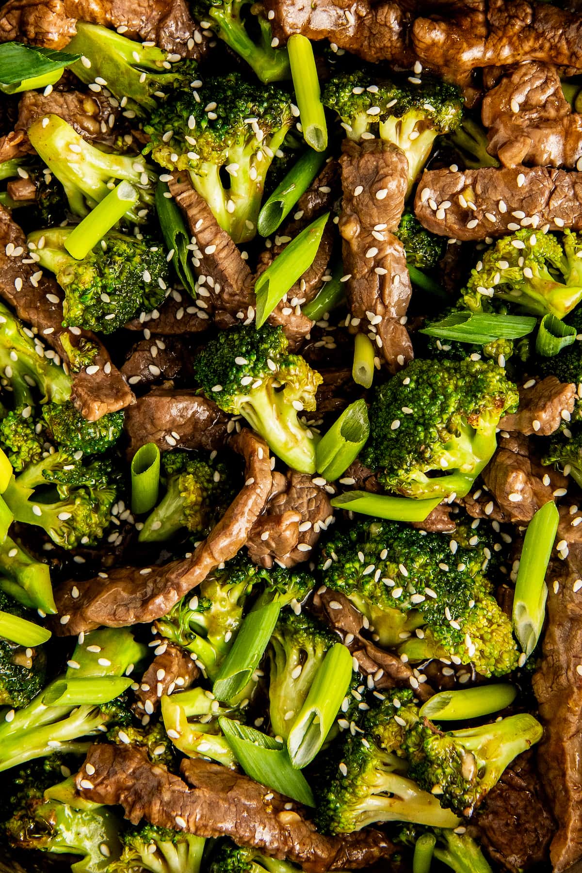 A close up of beef and broccoli stir fry garnished with sesame seeds.