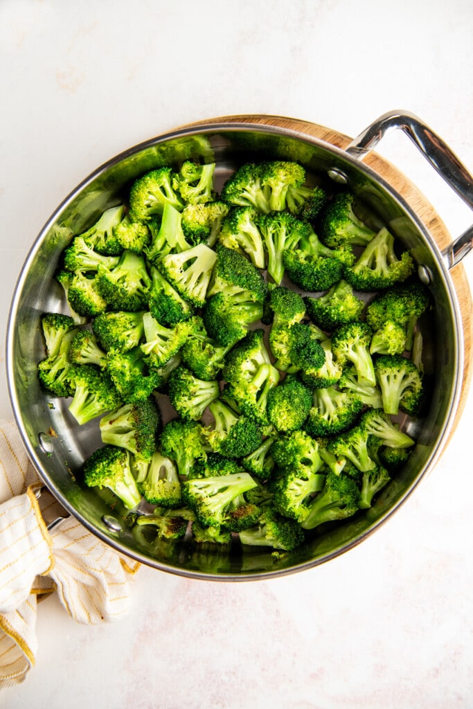 Cooking broccoli in a stainless steel pan.