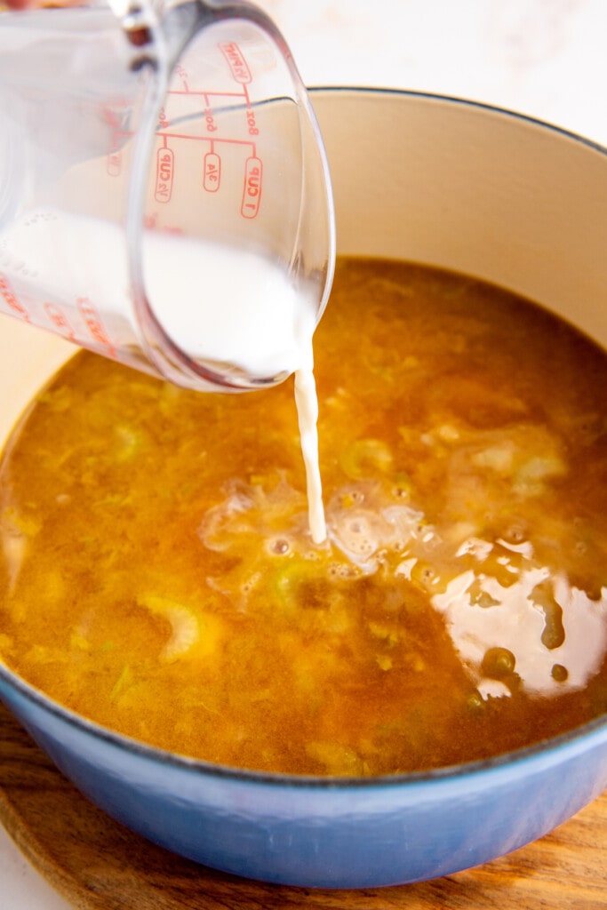 Pouring milk into the chicken broth and vegetables.
