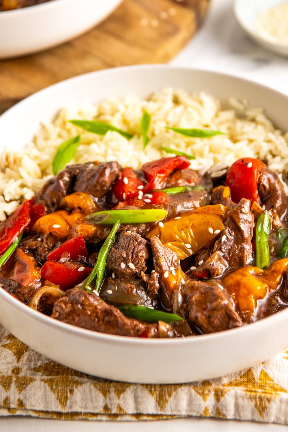 Close up of a bowl of slow cooker pepper steak with onions over white rice.