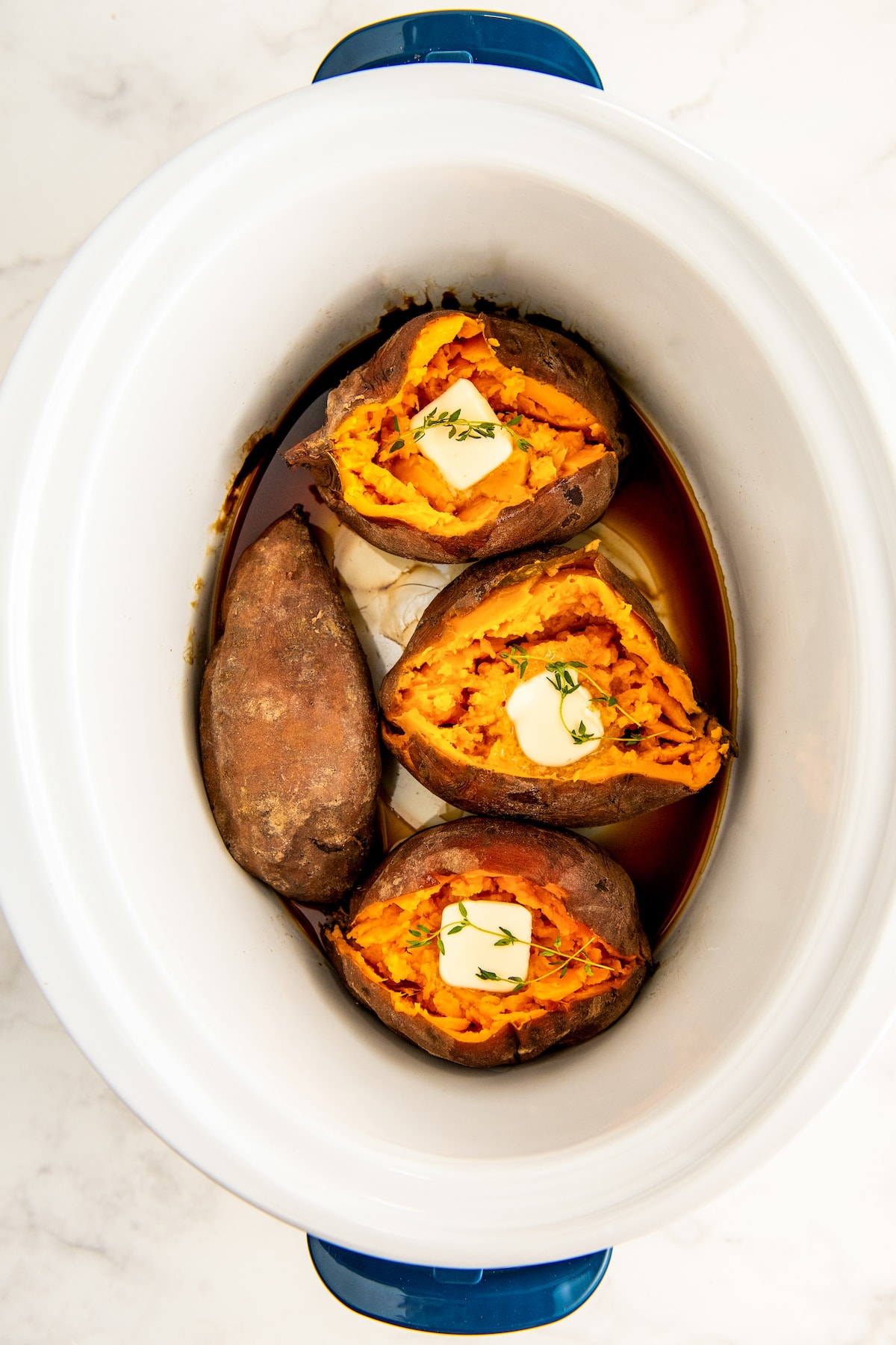 Slow cooker sweet potatoes cooked till tender, sliced open and filled with pads of butter. 