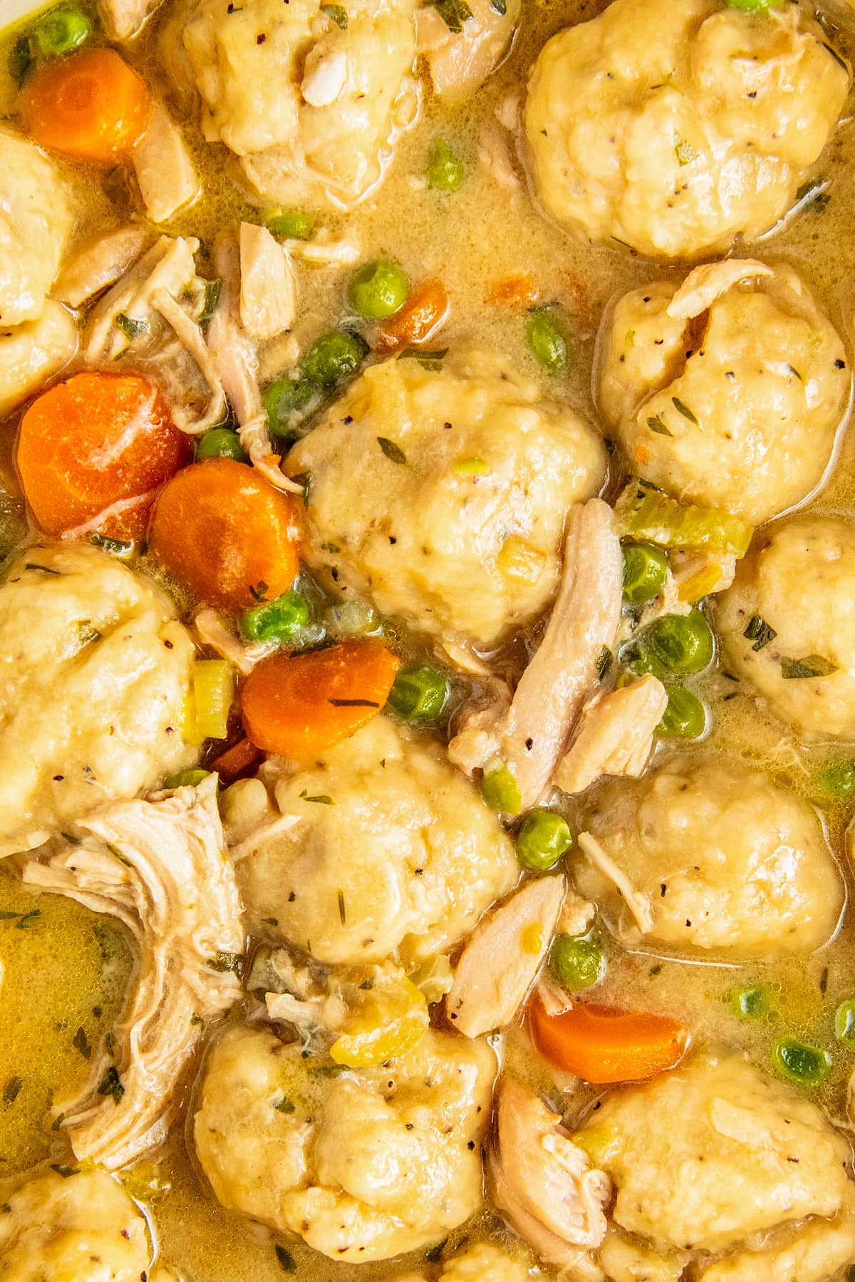 A close up view of several drop dumplings fully cooked in a chicken and dumplings dish.