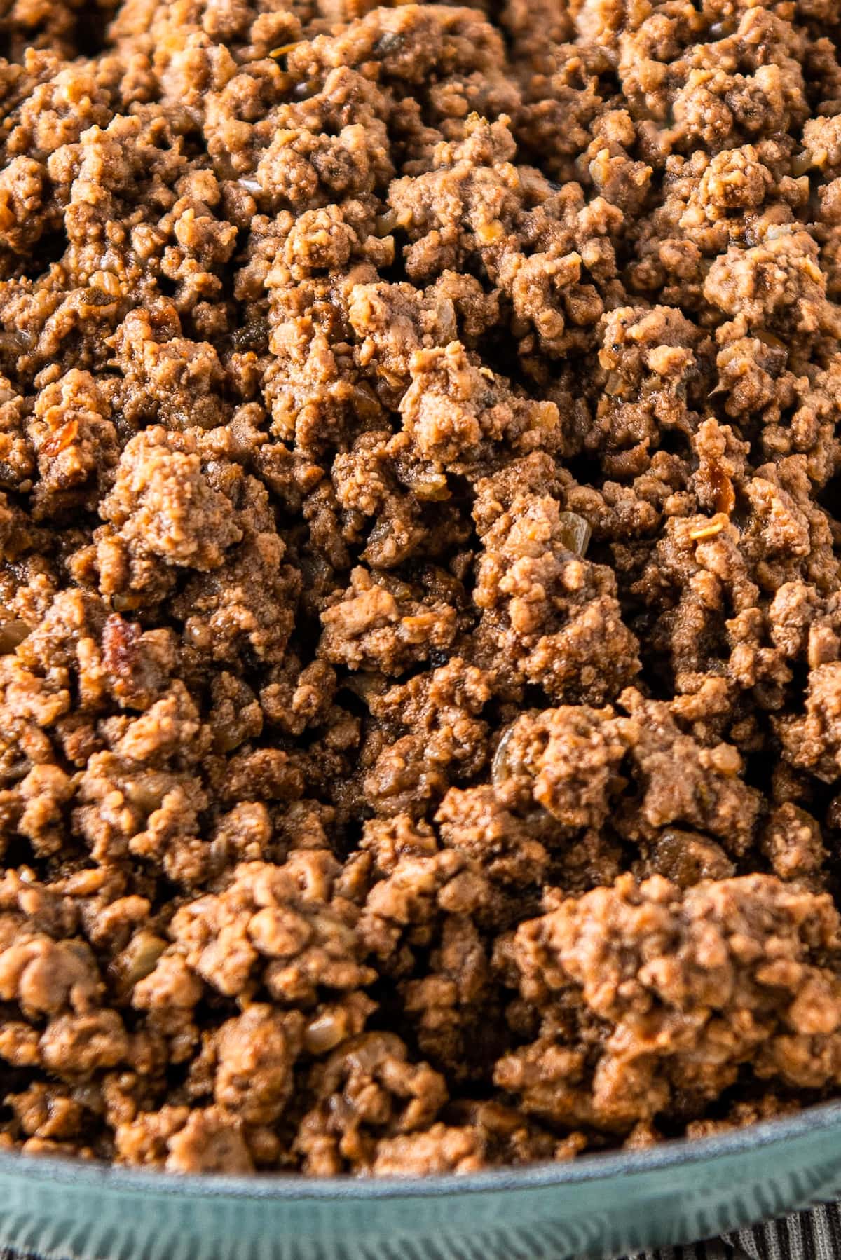 Crumbled and cooked ground beef in a blue skillet.