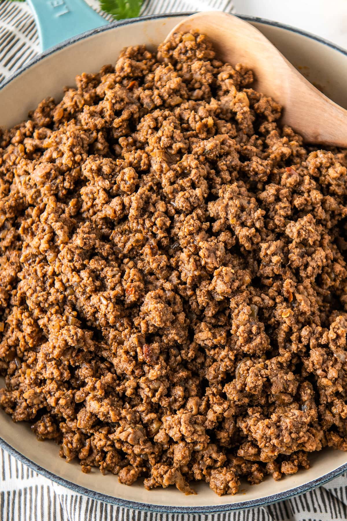 Ground beef in a skillet with a wooden spoon.