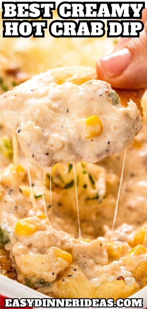 A cracker scooping out a bite of hot crab dip from a casserole dish.