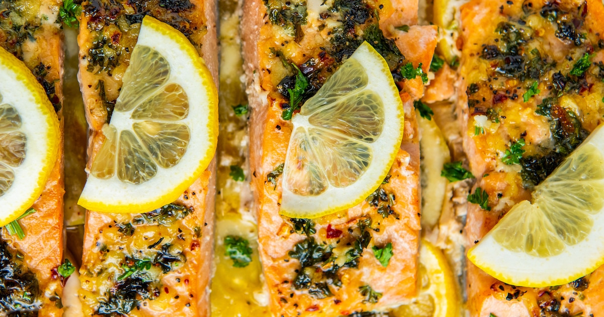 Lemon garlic salmon roasted on a sheet pan with fresh sliced lemons on top.