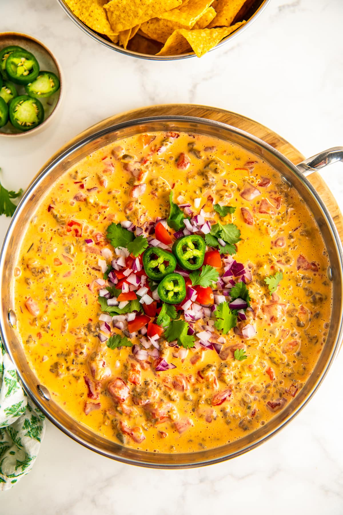 Creamy Sausage Cream Cheese Rotel Dip in a skillet garnished with red onions, jalapenos, cilantro, and tomatoes.