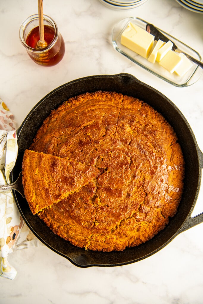 Taking out the first slice of sweet potato cornbread from the cast iron skillet.